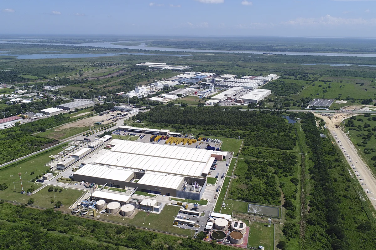 Vista aérea de un parque industrial con naves de producción, tanques y amplias zonas verdes alrededor